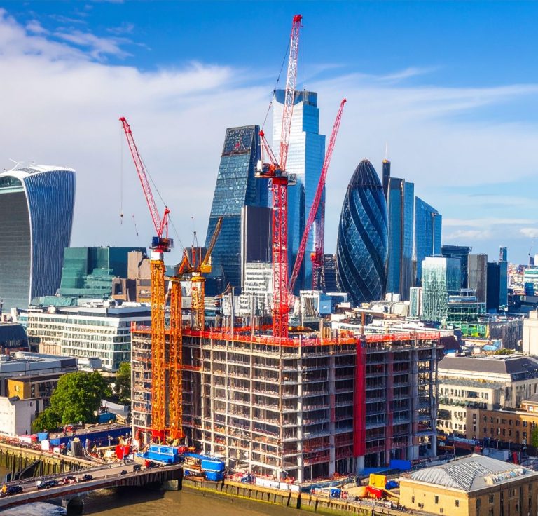 Invest in Infrastructure Construction site with cranes and modern buildings against a clear blue sky.